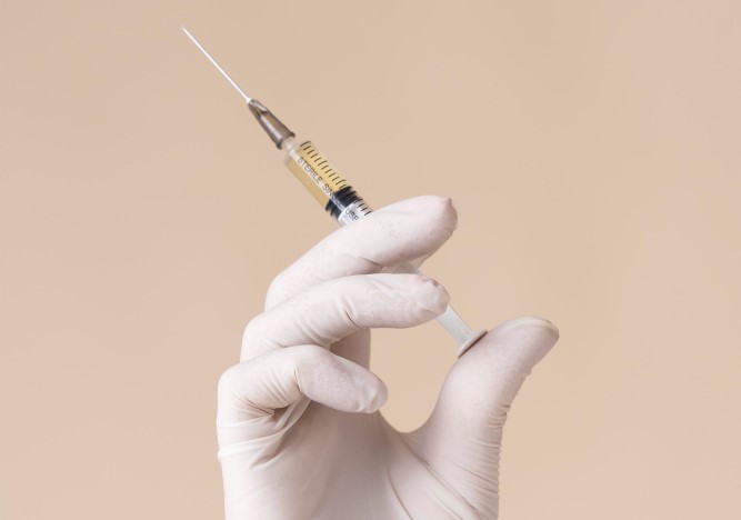 hand-with-latex-glove-holding-vaccine-syringe.jpg